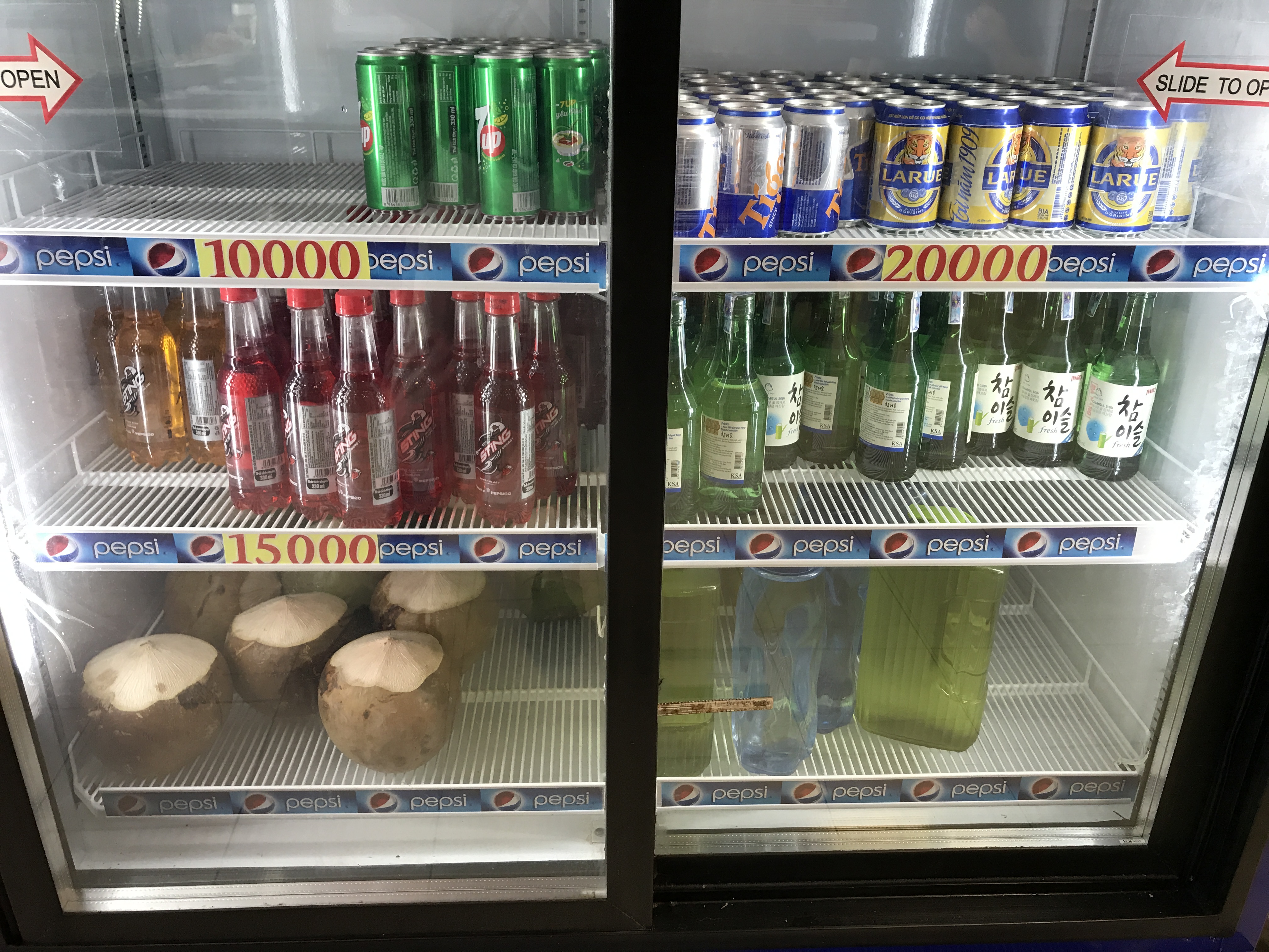 Refrigerator at a restaurant in Vietnam. It holds 7up, Sting energy drink, beer, and coconuts.